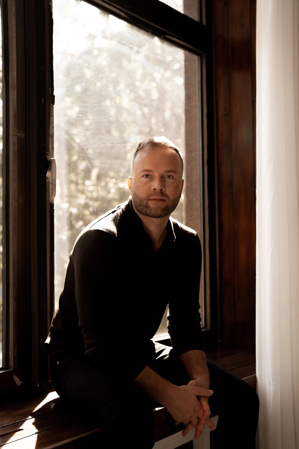 Martin Palmet sitting beside a sunlit window