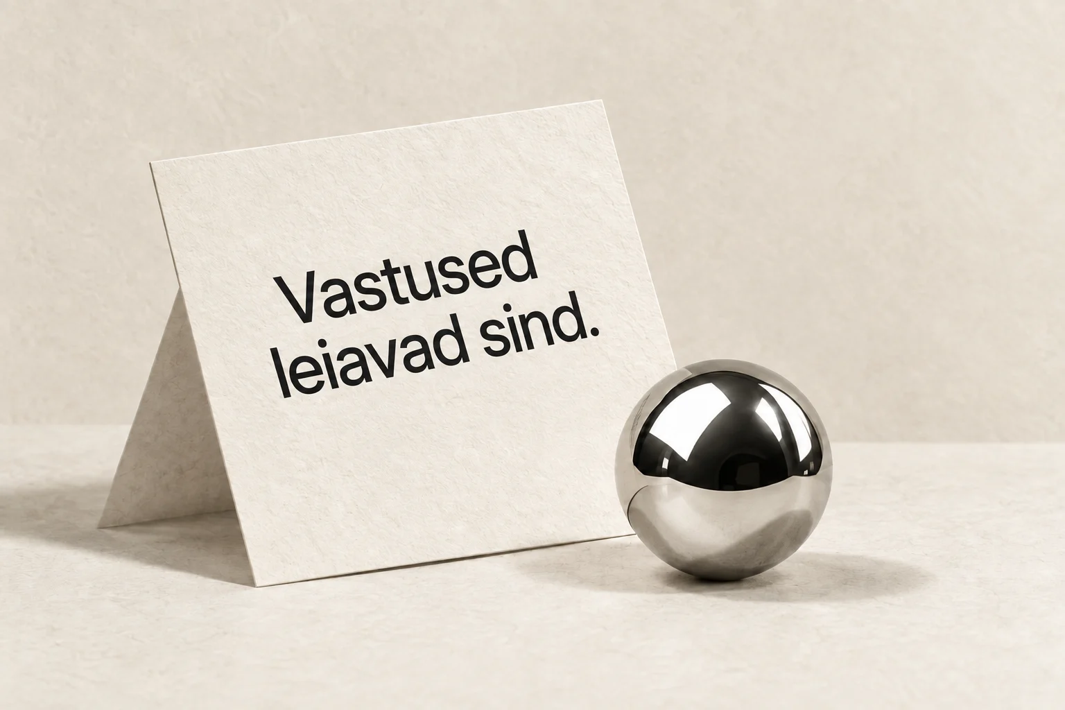 A paper card reading Answers find you beside a chrome sphere